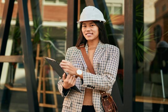 Young asian architect woman smiling happy writing on clipboard at the city.