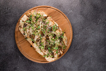 Italian pinsa romana with french escargot grape snails on dark background. Pinsa with snail, cheese, microgreen. Italian gourmet cuisine