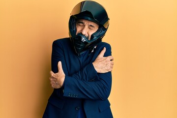 Middle age hispanic man wearing motorcycle helmet hugging oneself happy and positive, smiling...