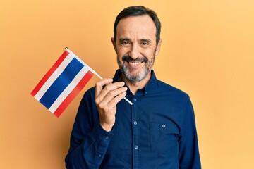 Middle age hispanic man holding philippines flag looking positive and happy standing and smiling...