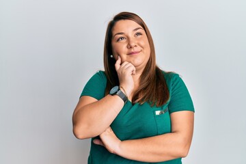 Beautiful brunette plus size woman wearing casual clothes thinking concentrated about doubt with...