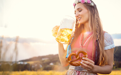 Bavarian woman with beer and pretzel in beautiful landscape