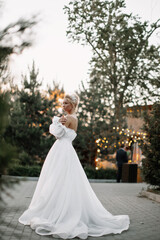 Fototapeta na wymiar bride in white weddind dress hugs herself by the shoulders