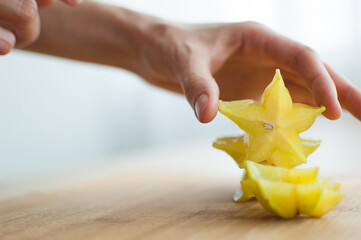 Female hands are holding slice of exotic ripe starfruit or averrhoa carambola. Healthy food, fresh organic star apple fruit