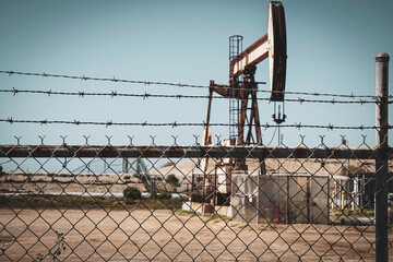 Vintage oil field with pump jack behind fence