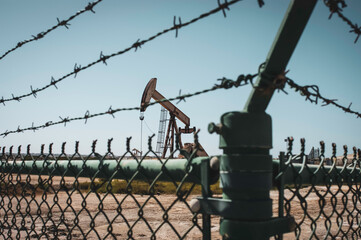 Vintage oil field with pump jack behind fence