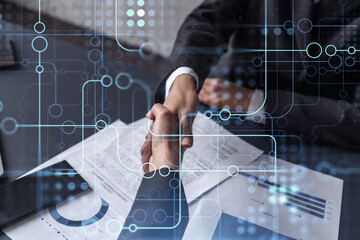 Handshake of two businesswomen who enters into the contract to develop a new software to improve business service at a company. Technological icons over the table with the document.