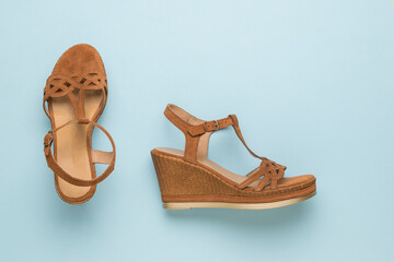 Stylish brown women's suede sandals on a blue background. Flat lay.