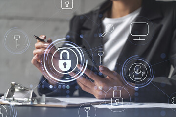 Businesswoman in formal wear signing the contract to prevent probability of risks in cyber security. Checking the phone. Padlock Hologram icons over the working desk.