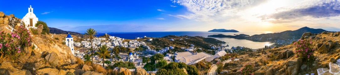 Naklejka na ściany i meble Breathtaking panoramic sunset view of Ios island. Chora town with churches and whitwashed houses. Popular tourist destination in Cyclades, Greece