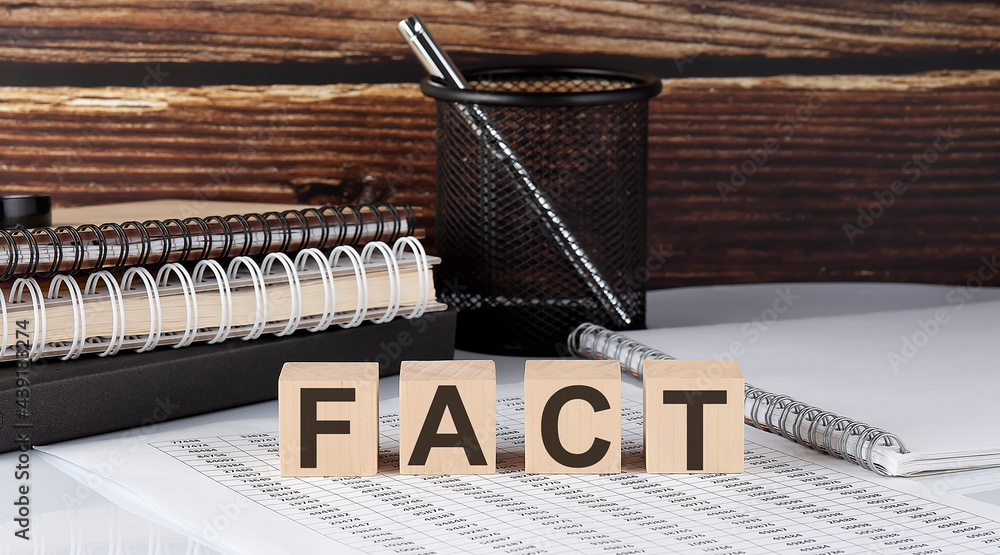 Aufkleber fact text on the wooden block with notebooks on the chart