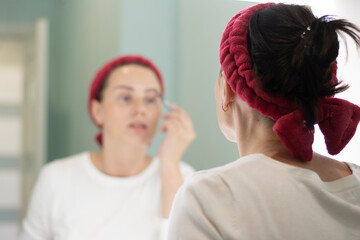 Woman applies makeup looking in the mirror, paints her eyebrows with a pencil