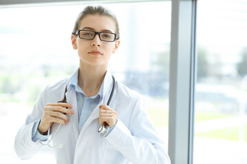 Beautiful woman doctor with stethoscope smiling charmingly and ready to help patients in the modern hospital. Medicine concept