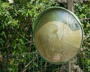 an old, faded and broken vehicle wide angle safety mirror