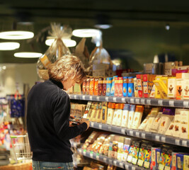 Young man shopping in supermarket, reading product information.