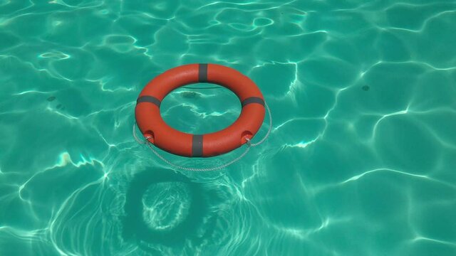 high angle view of an orange lifebuoy floating on clear water - life-saving and rescue concept 