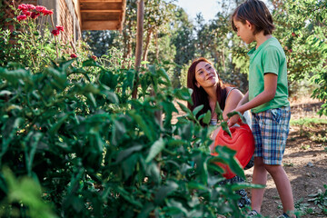 , watering the plants and weeds.Using gardening tools, gloves, scissors and watering can. gardening activity with a small child and his mother