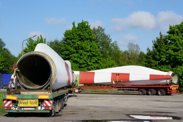 A view of a truck, a low-loader semi-trailer with oversized wind generator parts in the parking lot