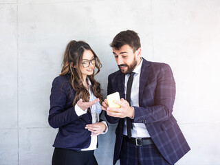 Businessman and businesswoman using a phone together in the office.
