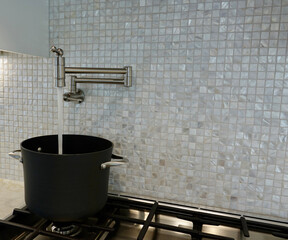 stock pot getting filled with water by pot filler on the stove