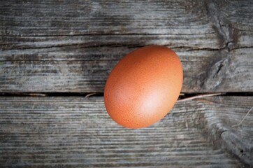 one brown chicken egg on a wooden background, top view, minimalism