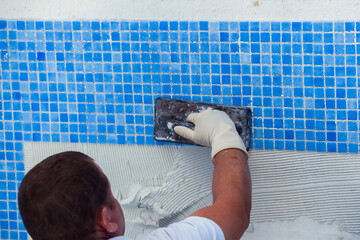Laying tile in the pool. Pool repairing work. - Powered by Adobe