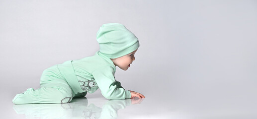 Little baby toddler wearing body set of slider and hat crawling on floor over white background