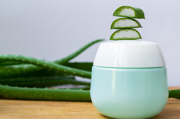 Whole and sliced aloe vera leaves and cosmetic jar on a wooden background. Natural cosmetics with aloe vera.