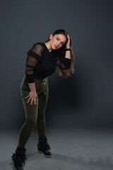 Portrait of beautiful model in black dress, hat and sunglasses on gray background