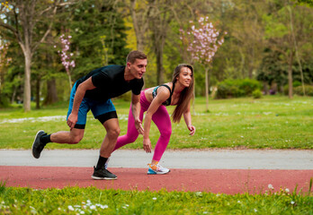 Fitness sport couple running jogging outside on stadium track