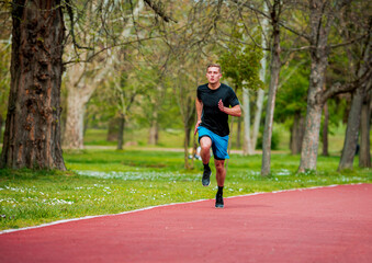 Young man jogging, running, exercising or stretching outdoors in park or nature