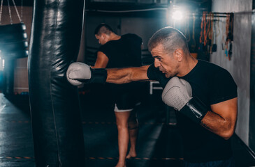 Concentrated young sportsman training thai boxing with punching bag