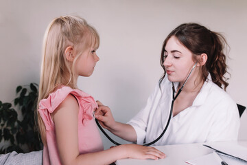 Doctor or nurse examining and listening girl using stethoscope during visit