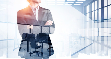 Businessman in black suit with arms crossed, blurred office room