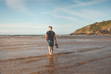 Young caucasian man walking at the beach