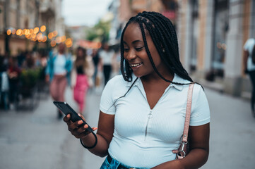 Beautiful young african american woman using smartphone in the city