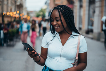 Obraz premium Beautiful young african american woman using smartphone in the city