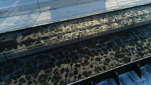 Long reservoirs with processed swirling water at contemporary purification station in winter evening bird eye view