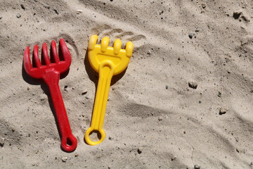 Colorful background with red and yellow rakes on sand