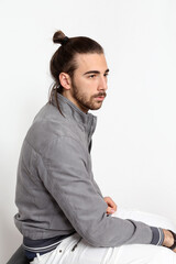 Attractive male model with long hair and beard posing in studio on isolated background. Style, trends, fashion concept.