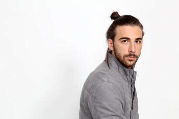 Attractive male model with long hair and beard posing in studio on isolated background. Style, trends, fashion concept.