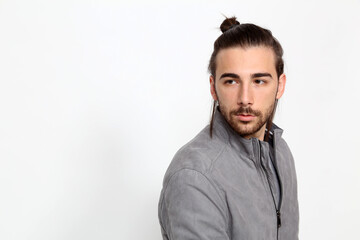 Attractive male model with long hair and beard posing in studio on isolated background. Style, trends, fashion concept.