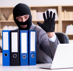 Criminal businessman wearing balaclava in office