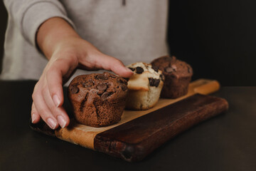 pastry chef presenting homemade vanilla and chocolate chips muffins  on a black background with sugar