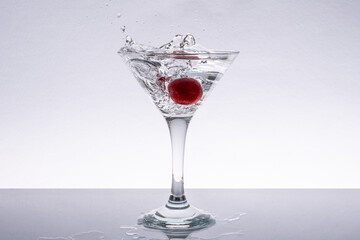 Fresh cherry falling into glass of water. Water splash.