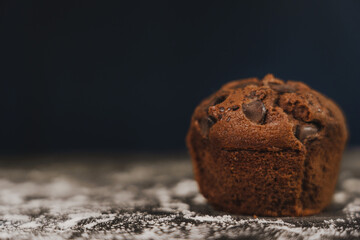 Homemade chocolate chips and vanilla muffin on a black background with sugar