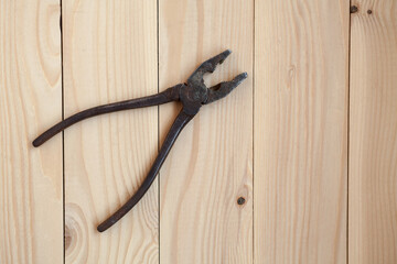 Old rusty pliers on a light wooden background. Pliers on the table, work concept.