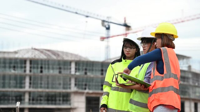 Young and senior Engineers discuss about work of large building underconstruction,Three people working on site of under construction