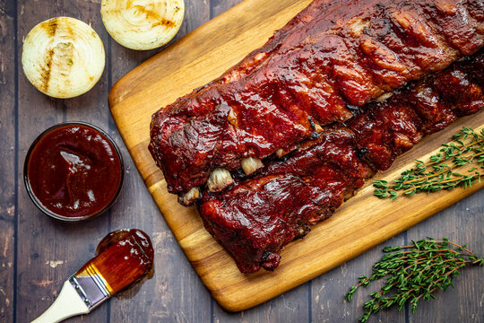 2 slabs of ribs with barbeque sauce on wooden cutting board