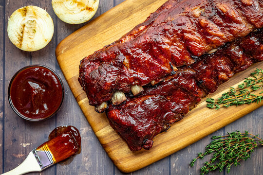 2 slabs of ribs with barbeque sauce on wooden cutting board
